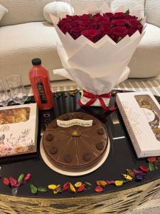 Una mesa con un pastel y un ramo de rosas. en عبر الاصالة, en Rafha