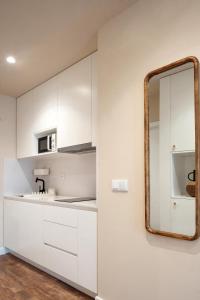 eine Küche mit weißen Schränken und einem Spiegel in der Unterkunft Foz Apartments in Figueira da Foz