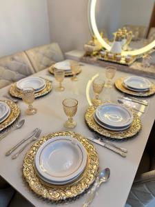 a table with gold and white plates and silverware at Magnífico APARTAMENTO de Charme - 3 quartos AR CONDICIONADOS SPLIT - Beira Mar, 2 banheiros, 2 Vagas Garagem, 4 Varandas, 2 Elevadores, Redes para Descanso, Wi-Fi, Air Fryer, Disney Plus, HBO Max, Guarda Sol, Cadeiras de Praia e Caixa Térmica in Guarapari