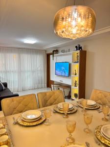 a dining room with a table with plates and wine glasses at Magnífico APARTAMENTO de Charme - 3 quartos AR CONDICIONADOS SPLIT - Beira Mar, 2 banheiros, 2 Vagas Garagem, 4 Varandas, 2 Elevadores, Redes para Descanso, Wi-Fi, Air Fryer, Disney Plus, HBO Max, Guarda Sol, Cadeiras de Praia e Caixa Térmica in Guarapari