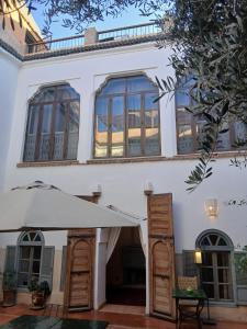 马拉喀什Riad le Jardin de Mina的一栋白色房子，门前撑着一把大伞。