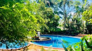 a swimming pool in a garden with trees at Advaitha Serenity Resorts in Kālvādi