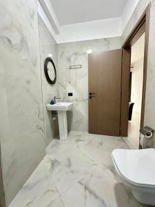 een witte badkamer met een wastafel en een toilet bij Actium in Vlorë