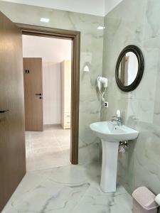 een witte badkamer met een wastafel en een spiegel bij Actium in Vlorë