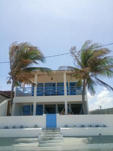 a building with palm trees in front of it at Pousada Caponga Praia Mar in Cascavel