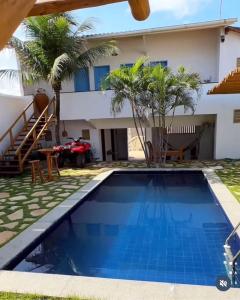 a villa with a swimming pool in front of a house at Pousada Caponga Praia Mar in Cascavel