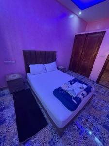 a bed in a room with a purple room at Résidence AGDAL in Dakhla