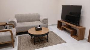 a living room with a couch and a tv and a table at W Hotel Apartment in Taif