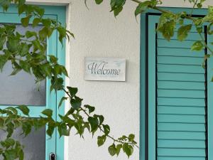 Beach House Ana في سوكوشان: باب أزرق عليه لافتة ترحيب على منزل