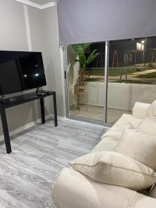 un soggiorno con divano e TV a schermo piatto di Hospedaje curauma a Lago Peñuelas