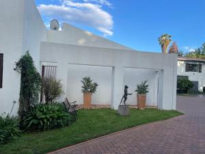 约翰内斯堡The Little Mongrel Deluxe Space Bryanston的一座白色建筑物前，矗立着一位行走的女性雕像。