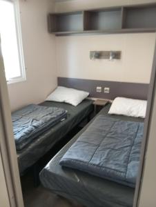 due letti in una piccola stanza con una finestra di Mobil-home 6 places dans camping 4 étoiles a Lit-et-Mixe