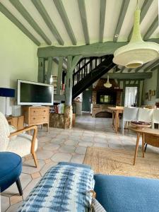 un soggiorno con divano, TV e camino di La chaumière confort et charme Normand a Saint-Pierre-le-Vieux