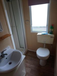 a bathroom with a toilet and a sink and a window at The Franklin in Saint Osyth +3 photos