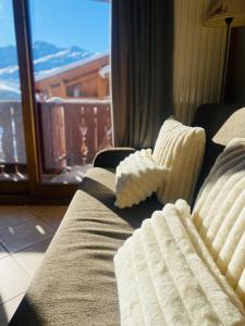レ・メニュアールにあるLe Chamois des Alpages de Reberty ski au piedの窓際に座る枕付きのソファ