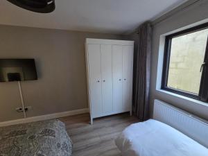 1 dormitorio con armario blanco y ventana en Kilgar gardens, en Kilcock 3 fotos más