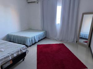 a room with two beds and a mirror and a red rug at Cada da lanny in Camaçari +11 photos