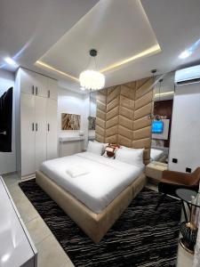 ウヨにあるPat Luxury Apartmentsの大きな白いベッドとシャンデリアのある寝室