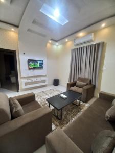 ハーイルにあるروعة أجا للشقق المخدومة غرفة وصالةのソファと椅子とテレビのあるリビングルーム