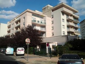a large white building with cars parked in front of it at Les Burgondes in Dijon