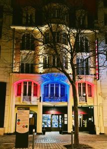 a building with red and blue windows and a tree at Hôtel Cecyl Reims Centre in Reims