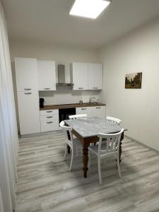 eine Küche mit einem Tisch und Stühlen sowie weißen Schränken in der Unterkunft Elena's apartment - casa gialla in Quartesana