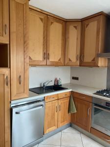 a kitchen with wooden cabinets and a stainless steel dishwasher at La Maison des Pierres in Zinswiller +3 photos
