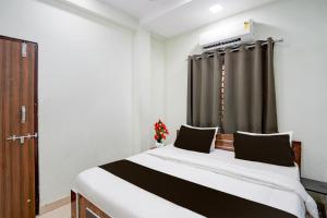 Townhouse Shri Mahakaleshwar Jyotirlinga Ujjain Formerly Hotel Shikhar Darshan في اوجاين: غرفة نوم بسرير وستارة سوداء