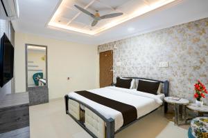 Townhouse Shri Mahakaleshwar Jyotirlinga Ujjain Formerly Hotel Shikhar Darshan في اوجاين: غرفة نوم بها سرير ومروحة سقف