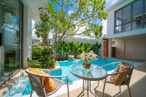 普吉镇云栖别院 Cloudrest Villa的带玻璃桌椅和游泳池的露台