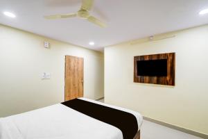 a bedroom with a bed and a tv on the wall at Hotel O R Square NARSINGI in Gundipet