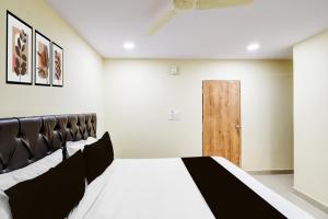 a bedroom with a bed and a wooden door at Hotel O R Square NARSINGI in Gundipet