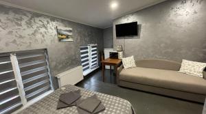 a bedroom with a couch and a tv on a wall at Family2 in Mukacheve