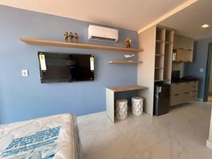Una sala de estar con un televisor en una pared azul. en Flat na melhor localização João Pessoa, en João Pessoa