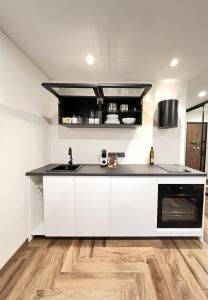 a white kitchen with a sink and a stove at Tėčio ir Dukters pajūrio apartamentai - Šventojoje in Palanga