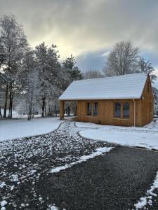 a wooden cabin in the snow with a snow covered driveway at Chalet Chalus in Châlus