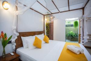 Un dormitorio con una cama con almohadas amarillas y blancas. en Sleeperwood Villa, en Unawatuna