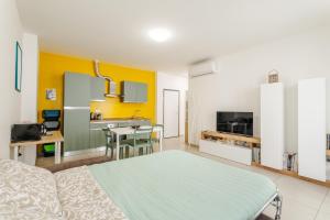 a room with a bed and a kitchen with yellow walls at FaCentro - Free WiFi & Air Conditioning in Faenza