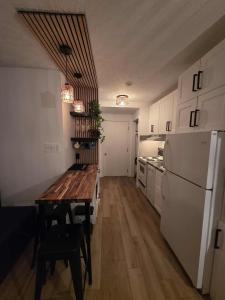 梅戈格Au p'tit cocon sur le lac的厨房配有木桌和白色冰箱。