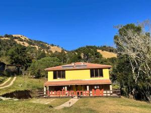 una casa gialla con sedie arancioni di fronte di Chale Manticas Blue na Serra da Mantiqueira a Córrego do Bom Jesus