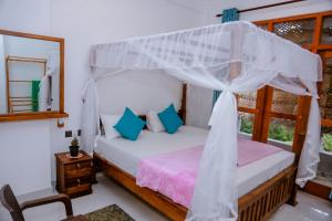a bedroom with a bed with a canopy at Femingo by Costels in Hiriketiya
