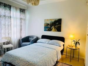 a bedroom with a bed and a chair at Apolonia Transient House- The White Room in Baguio