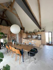 una sala da pranzo con un grande tavolo in legno e sedie di Grange transformée a Crucheray
