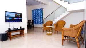 sala de estar con sillas de mimbre y TV en The Sea Garden, en Mahabalipuram 13 fotos más
