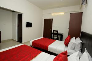 una camera d'albergo con due letti con cuscini rossi di Super Hotel O Technopark Formerly Le Frank a Trivandrum