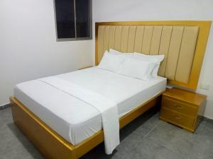 a bedroom with a large white bed with a wooden headboard at Hotel La Dorada Sincelejo in Sincelejo