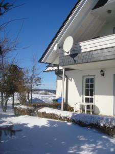 a white house with a bench in the snow at Mein Sauerland in Medebach +7 photos