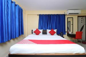 OYO Hotel O Maa Tara Guest House في Jādabpur: غرفة نوم بسرير كبير مع ستائر زرقاء