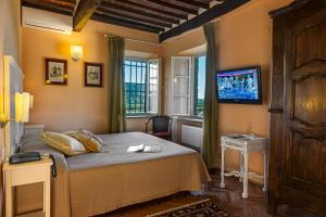 een slaapkamer met een bed en een tv aan de muur bij Hotel Villa Volpi in Lucca