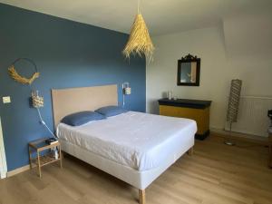 a bedroom with a white bed and a blue wall at Les rives enchantées in Courçay
